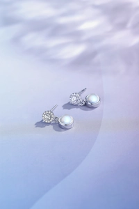 Macro detail of round moonstone earrings with micro-pave diamonds on silk background