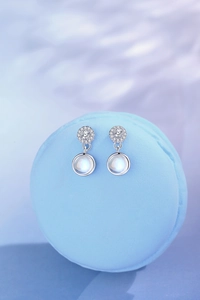 Macro detail of silver drop earrings with moonstone and pavé-set round diamonds