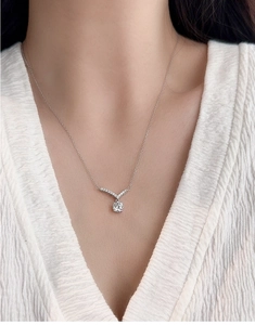 Close-up of sparkling V-shaped 925 silver necklace with moissanite pendant on a model