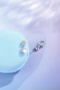 Macro detail of moonstone drop earrings with pave diamonds on light blue macaron