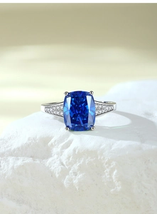 Macro shot of cushion-cut royal blue sapphire ring with micro-paved silver band details