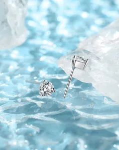 Macro shot of 925 silver stud earrings with round-cut stones on ice water background