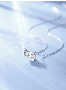 Macro shot of S925 sterling silver necklace featuring pear and round cut moissanite pendants
