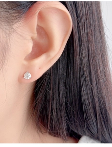 Close-up of a minimalist three-prong round-cut stud earring worn on a female ear lobe