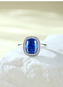 Macro shot of cushion-cut royal blue sapphire ring with halo setting on a stone base