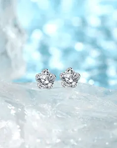 Macro shot of S925 silver star earrings with round-cut crystals on icy blue background