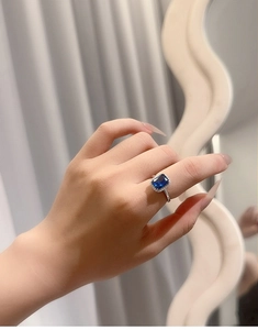 Detailed view of an S925 silver ring with a large rectangular blue gemstone on a finger