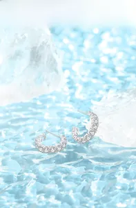 Macro shot of silver S925 C-shaped earrings with sparkling cubic zirconia pavé stones