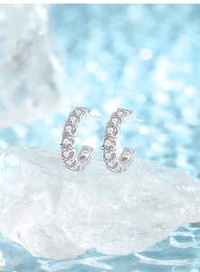 Close-up of sparkling S925 silver C-shaped stud earrings with full pavé cubic zirconia