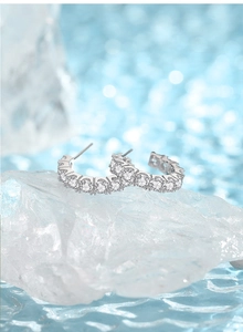 Macro shot of silver C-shaped stud earrings with pave-set sparkling round cubic zirconia