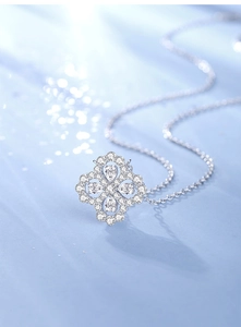 Macro shot of silver clover pendant with water-drop shaped stones and pavé setting