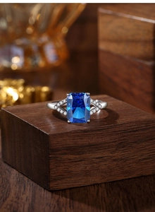 Detail of radiant cut royal blue sapphire ring with crisscross silver band and stones