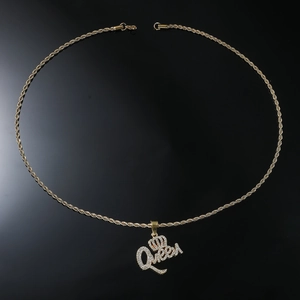 Macro shot of gold-plated Queen crown pendant with cubic zirconia on a rope chain