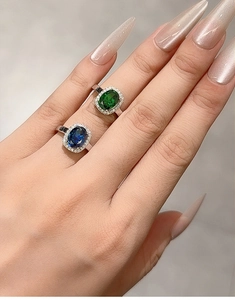 Close-up of S925 silver rings with radiant cut sapphire and emerald gemstones on hand