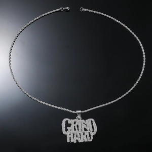 Macro shot of silver hip hop necklace showing iced out Grind Hard pendant and rope chain