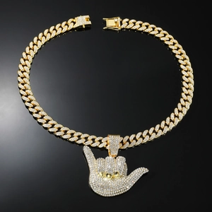 Détail macro du collier cubain doré avec pendentif geste de main hip hop serti de strass
