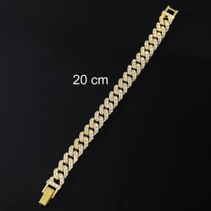 Detalle macro de una pulsera cubana dorada de 20 cm con pedrería de diamantes de imitación