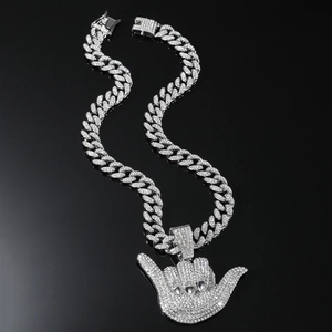 Gros plan d'un pendentif Shaka serti de strass sur une chaîne cubaine argentée