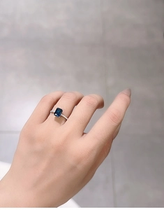Close-up of radiant cut sapphire blue gemstone ring with micro-pave diamond band on hand
