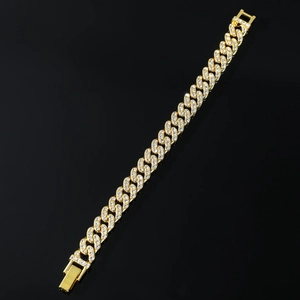 Vista macro de pulsera cubana dorada con circonitas incrustadas y detalle de cierre pulido