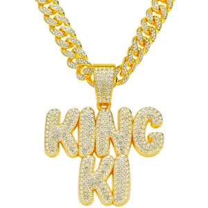 Macro detail of iced-out KING KO pendant with pavé-set crystals on gold Cuban link chain