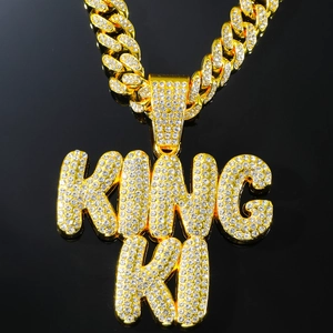 Macro shot of iced-out gold KING letter pendant with sparkling crystal Cuban link chain