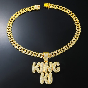 Macro view of iced out KING KI letter pendant on gold Cuban link chain with white zircons