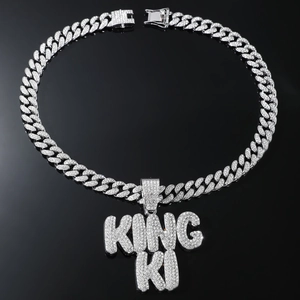 Macro shot of silver hip hop Cuban chain featuring iced out KING KI letter pendant