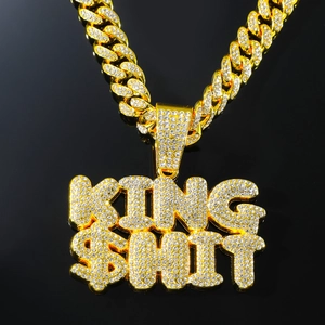 Macro shot of gold-plated iced out KING $HIT letter pendant on thick cuban chain