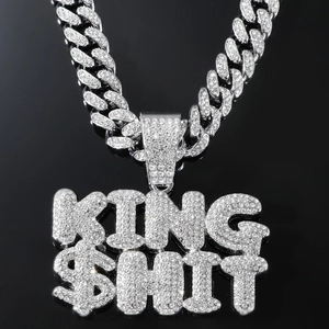 Detail view of silver iced-out Cuban chain necklace with sparkling KING $HIT letter pendant