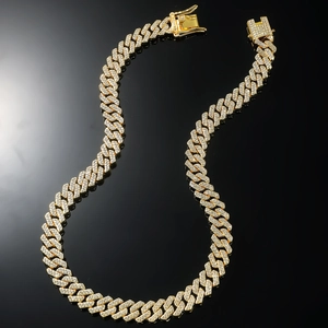 Iced out gold Cuban link necklace with sparkling crystals on black mirror surface