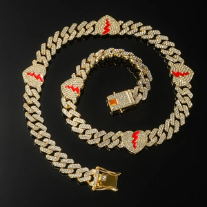 Detail of gold Cuban chain set with white rhinestones and red broken heart pendants