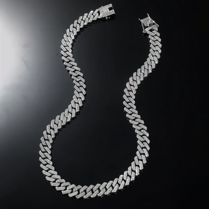 Close-up of silver Cuban link necklace featuring iced-out pavé crystals on black background