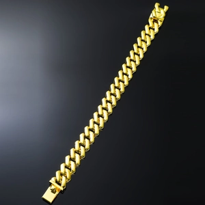 Macro shot of a high-polish 18K gold Cuban link bracelet with a secure clasp on black background