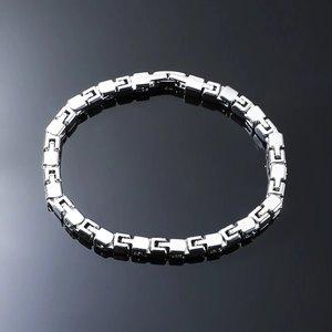 Close-up of geometric link chain bracelet with industrial design on black reflective surface