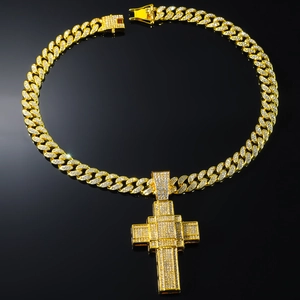 Gros plan détaillé du pendentif croix dorée sertie avec sa chaîne gourmette de style hip hop