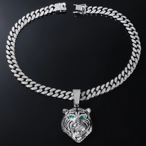 Macro-opname van zilveren leeuwenhanger met groene ogen en een iced-out Cubaanse schakelketting