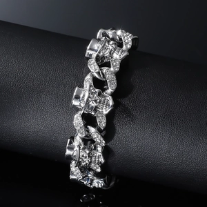 Close-up of silver Cuban link bracelet with pavé rhinestones and skull charm on leather