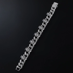 Close-up of punk style silver Cuban chain bracelet with skull charms and pavé crystals