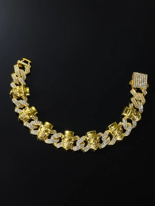Close-up of golden Cuban link bracelet with skull charms and pave-set white crystals
