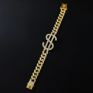 Détail d'un bracelet gourmette doré avec signe dollar serti de zircons et fermoir sécurisé