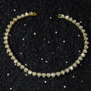 Vista macro de un collar de cadena de corazón dorado con circonitas sobre fondo mineral negro