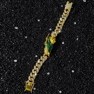 Détail d'un bracelet gourmette doré serti de zircons avec pendentif Saint Jude vert