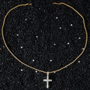 Vue macro d'un collier chaîne torsadée dorée avec pendentif croix en zircon sur fond noir