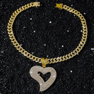 Détail du collier à chaîne cubaine dorée avec pendentif cœur ajouré serti de strass brillants