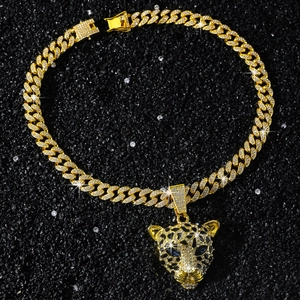Détail d'une chaîne cubaine dorée et pendentif léopard aux yeux de pierres bleues