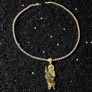 Détail du pendentif Saint Jude doré avec pierres vertes sur une chaîne de tennis chic