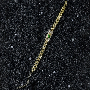 Close-up of golden rose link bracelet with green gemstone and St. Jude charm