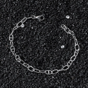 Polished silver stainless steel pig nose link chain bracelet on black gravel background