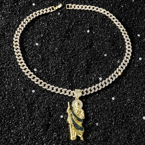 Close-up of gold Cuban chain and St. Jude pendant with green stones and sparkling zircons